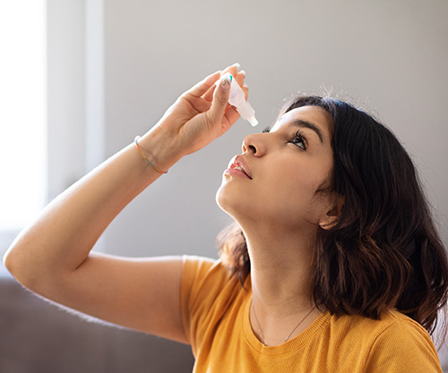 a woman taking eye drop medicine