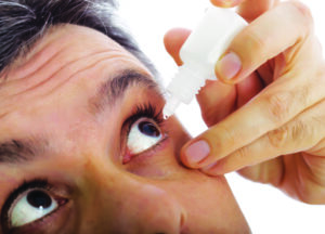 man taking eye drop medicine