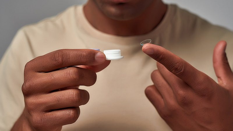 man holding contact lens and lens case