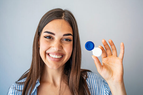 a woman holding a contact lens case: proper handling of contact lenses can prevent acanthamoeba keratitis infection