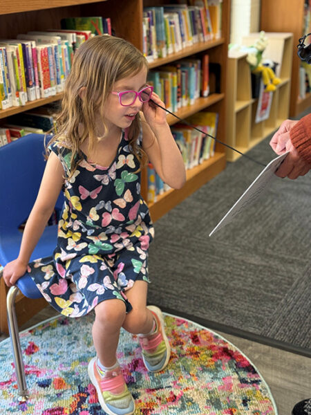 a child wearing glasses having her vision screened