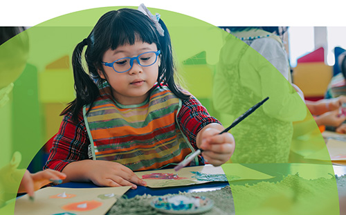 a girl wearing glasses doing artwork in school